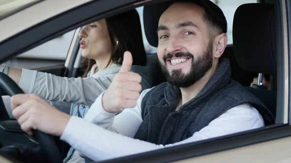 Visitando concesionario de coches. Hermosa familia está hablando y sonriendo mientras está sentado en su nuevo coche. joven muestra el dedo hacia arriba — Foto de Stock