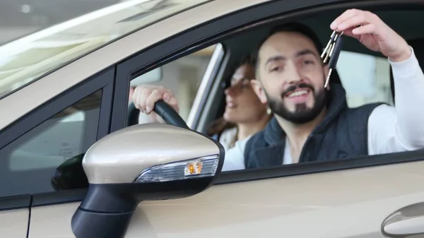 Visitando concesionario de coches. Hermosa familia está hablando y sonriendo mientras está sentado en su nuevo coche. joven muestra el dedo hacia arriba — Foto de Stock