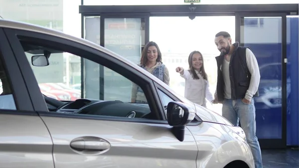Familia joven entra en concesionario de coches para elegir el coche para comprarlo — Foto de Stock
