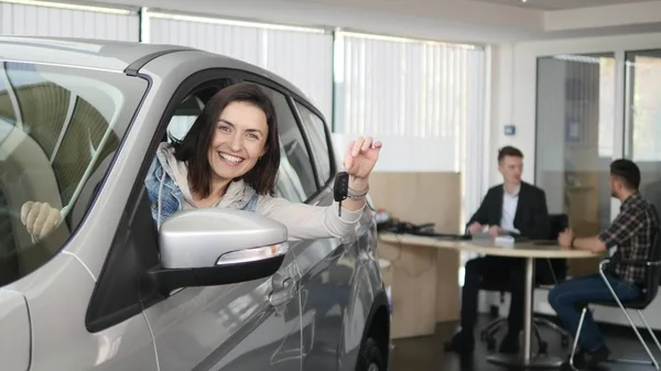 Mulher feliz mostrando a chave de seu carro novo. Auto negócio, venda de carros, tecnologia e conceito de pessoas - macho feliz com revendedor de carros em show de automóveis ou salão de beleza — Fotografia de Stock