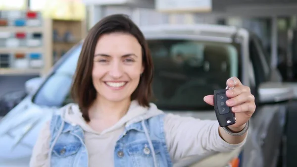 Mujer joven sosteniendo las llaves de coche nuevo auto y sonriendo a la cámara —  Fotos de Stock