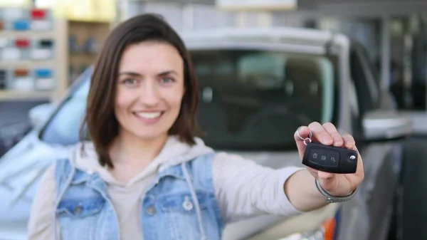 Yeni araba otomatik tuşu tutmakta ve kameraya gülümseyen genç kadın — Stok fotoğraf