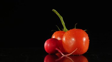su damlaları siyah bir zemin üzerine taze domates ve turp döndürmek