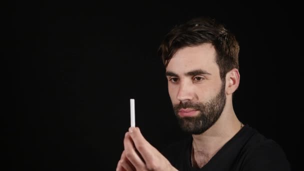 Мужчина выбирает между электронной или нормальной сигаретой на черном фоне — стоковое видео