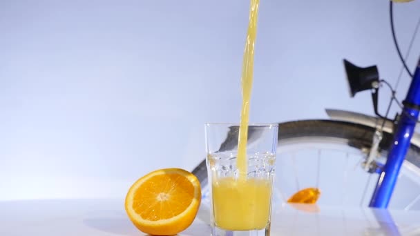 Rotation du jus d'orange et d'orange sur la table bicyrcle sur fond — Video