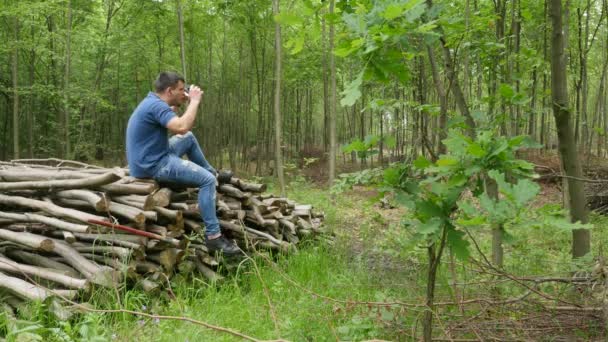 Um jovem bonito na floresta ouve música de fones de ouvido — Vídeo de Stock