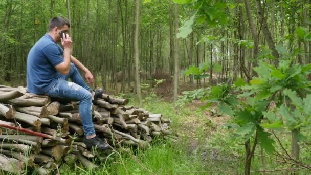 Młody człowiek rozmawia przez telefon w lesie — Wideo stockowe