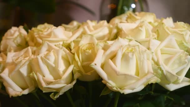 Close-up tiro de rosas frescas de cor branca com hastes verdes e folhas dispostas em cachos para venda em loja floral — Vídeo de Stock