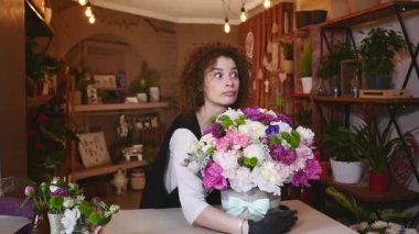 buket üstünde okul sırası ile gülümseyen Çiçekçi Çiçek dükkanında çalışan ve kameraya, arayan genç bir kadın