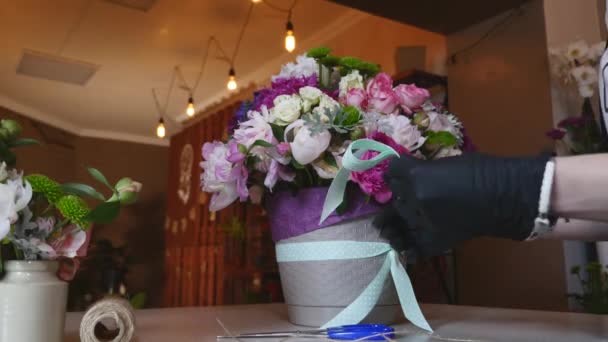 Vista superior de las manos de florista haciendo ramo de flores con cinta decorativa — Vídeo de stock