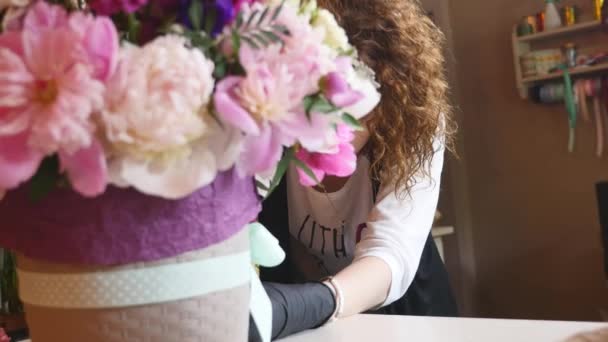 Вид сверху на флористические руки, делающие букет цветов с декоративной лентой — стоковое видео