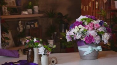 Renkli peonies ve gül ve mavi şerit beyaz masa üzerinde oluşan close-up. Arka plan çiçek Dükkanı