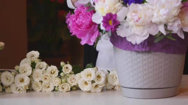 Κοντινό πλάνο ανθοκόμος κάνει μια ανθοδέσμη των λουλουδιών. Peone και τριαντάφυλλα — Αρχείο Βίντεο