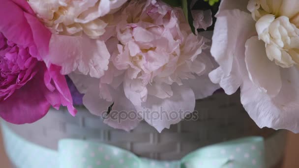 Primer plano del ramo de coloridas peonías y rosas y cinta azul en la mesa blanca. En la tienda de flores de fondo — Vídeos de Stock