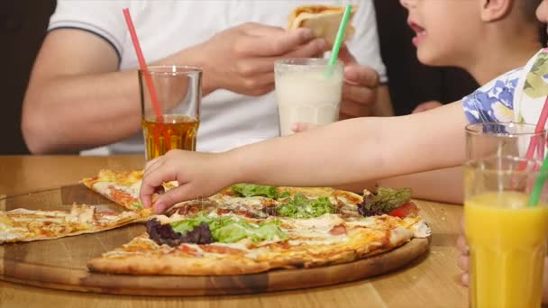 O familie de patru oameni mănâncă o pizza împreună într-o cafenea. — Videoclip de stoc