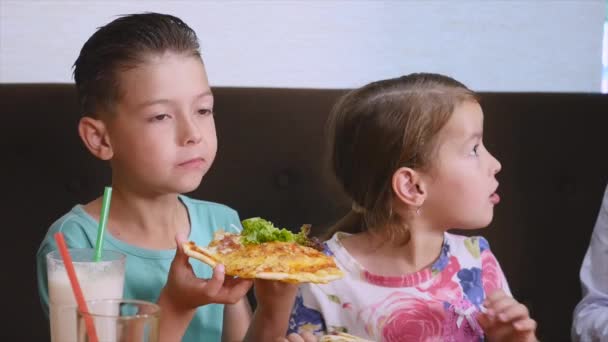 Детям весело есть пиццу в кафе — стоковое видео