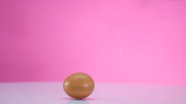 Bir tablo üzerinde pembe bir arka plan üzerinde yumurta döndürme