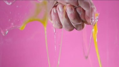 Bir yumruk sıkıştırılmış el pembe bir arka plan üzerinde yumurta yok eder.