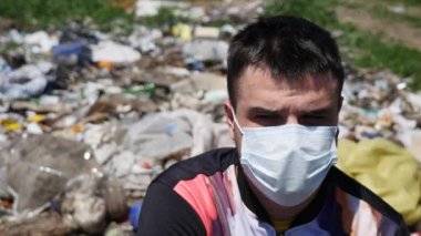 Maskeli adam çöp üzerinde oturuyor