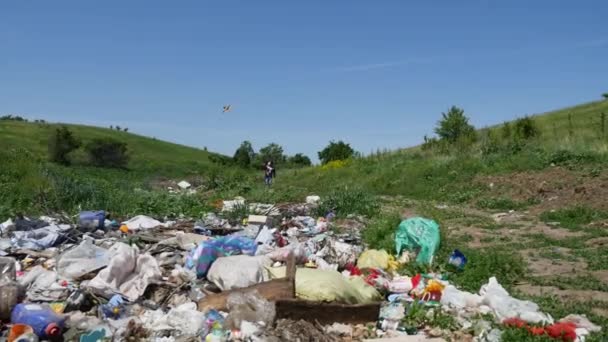 Человек в маске бегает с воздушным змеем рядом с кучей мусора — стоковое видео