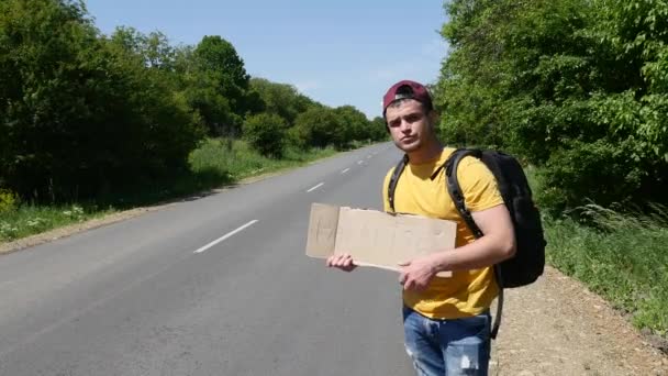 Bir sırt çantası ve bir işaret ile bir araba sarı tişört turist yakalar — Stok video