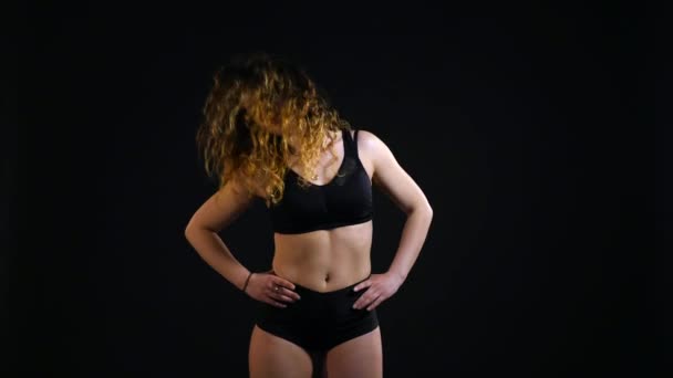 Спортивная девушка делает упражнения на черном фоне — стоковое видео