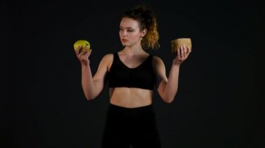 Hamburger ya da bir siyah arka plan üzerine izole elma arasında seçme şişman mutlu bir kadın portresi