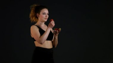 Mutlu kız siyah arka plan üzerine taze çilek ile