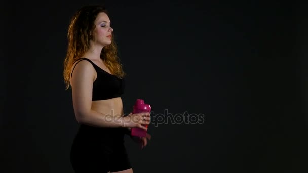 Спортсменка п'є з пляшкової води, жінка в спортзалі насолоджується прісною водою, спраглою жінкою після спорту, портретна брюнетка п'є мінеральну воду, здорове життя, баланс води в організмі — стокове відео
