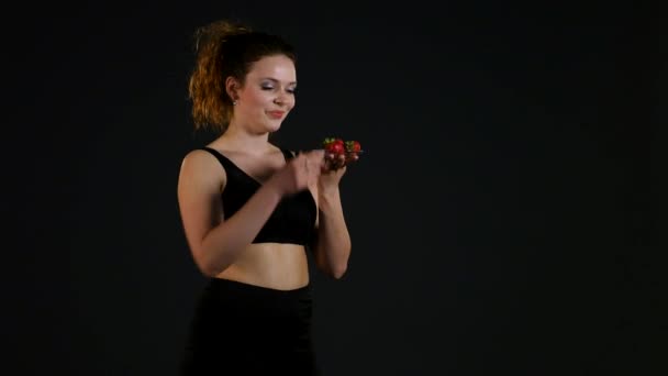 Fiatal, boldog lány fekete háttér friss eperrel — Stock videók