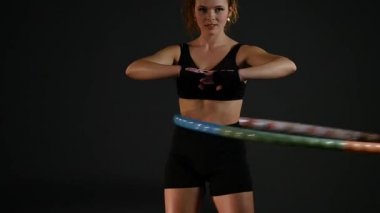 genç kadın siyah arka plan üzerine bir çember egzersiz yapıyor