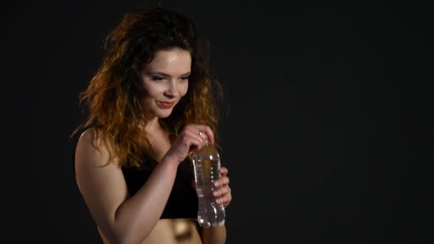 Fit mujer beber agua de la botella sobre fondo negro — Vídeo de stock