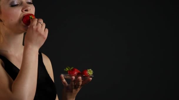 Joven chica feliz con fresas frescas sobre fondo negro — Vídeos de Stock