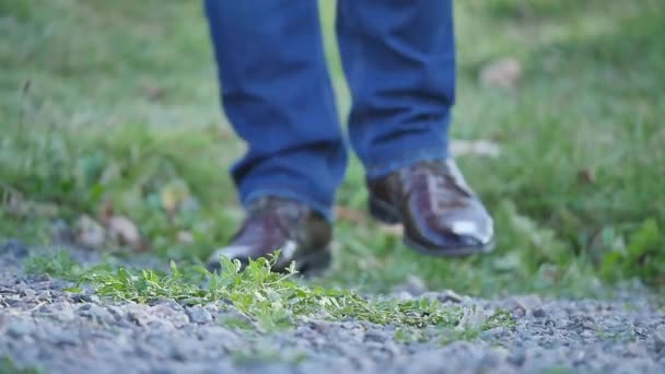 Jonge man loopt op straat. Close-up van benen in jeans en laarzen — Stockvideo