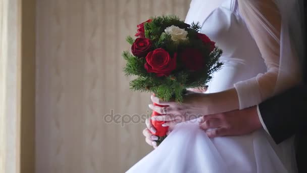 Счастливые жених и невеста стоят у окна. Молодая женщина держит в руках красивый свадебный букет. Пара смотрит в широкое окно отеля. Медленное движение — стоковое видео