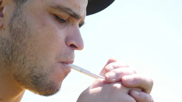 Adam bir sigara yakıyor, mesafe ve sağlar lense duman içine görünüyor — Stok fotoğraf