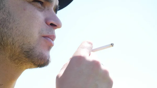 Facet zapala papierosa, wygląda na odległość i pozwala dymu w obiektyw — Zdjęcie stockowe