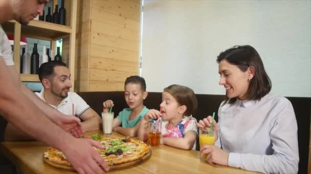 Uma família de quatro pessoas comendo uma pizza juntos em um café — Vídeo de Stock