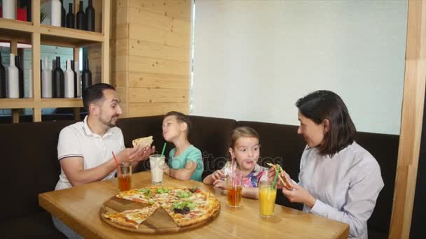 En familj på fyra äta en pizza tillsammans på ett café — Stockvideo