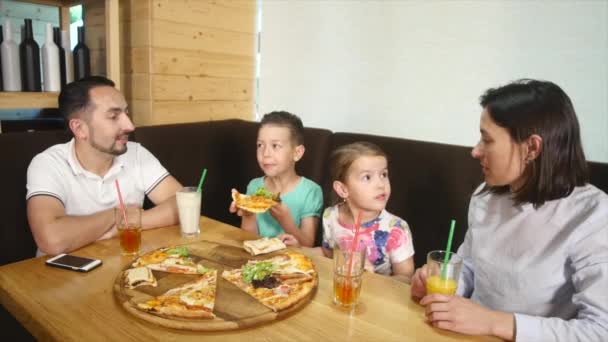 En familj på fyra äta en pizza tillsammans på ett café — Stockvideo