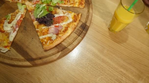 Händerna tar pizza nedskärningar från plattan på bord — Stockvideo