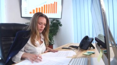 Ofiste belgelerle çalışan güzel genç bir kadın.