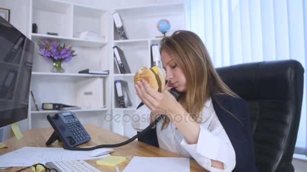 Mujer ocupada hablando por teléfono mientras toma una hamburguesa — Vídeo de stock