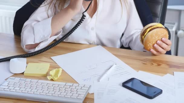 Drukke vrouw praten over de telefoon terwijl het hebben van Hamburger — Stockvideo