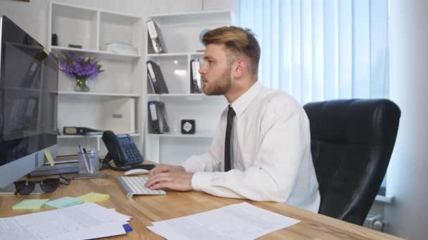 Een gefrustreerd zakenman begint te bang in hoofd op zijn computer — Stockvideo