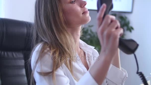 Unga attraktiva affärskvinna talar på telefon med benen på bordet på kontoret — Stockvideo