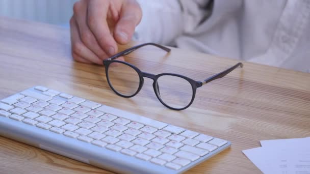 Office jelenet jegyzetek és dokumentumok és szemüveg. Egy fiatal mans kezében dolgozik a laptop — Stock videók