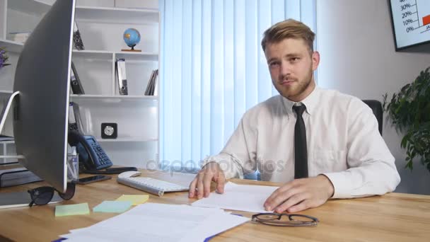 Ritratto di un giovane barbuto seduto nel suo ufficio a lavorare su un computer — Video Stock