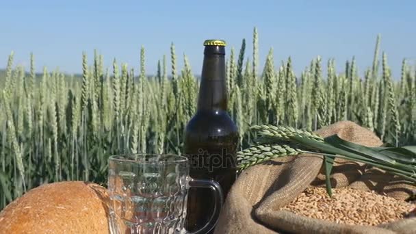 Хлеб, квас и мешок пшеницы на столе в пшеничном поле в солнечный облачный августовский день — стоковое видео