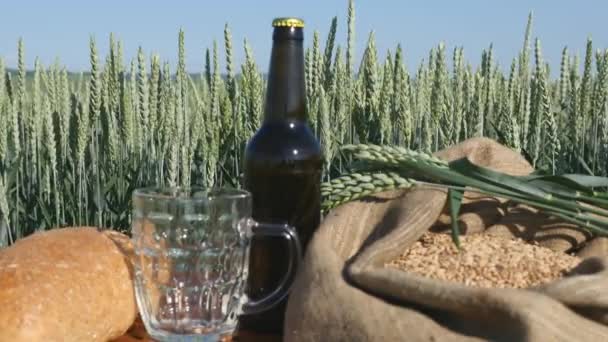 Bread, Kvass and a bag of wheat on the table in wheat field on sunny cloudy windy August day — Stock Video